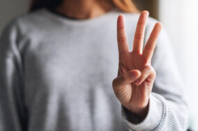 a-woman-making-and-showing-number-three-hand-sign