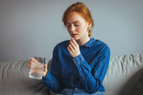 young-beautiful-woman-taking-tablet-with-glass-of-fresh-water-c