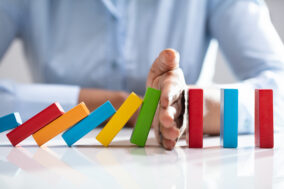 businesswoman-stopping-dominoes-on-desk